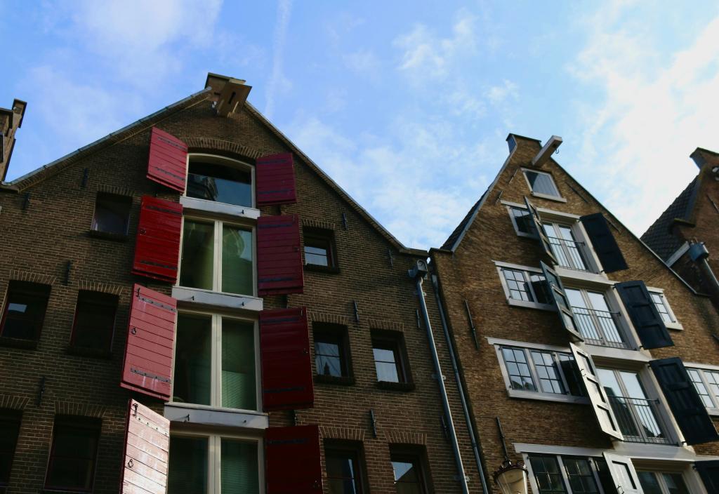 Traditionele Nederlandse huizen in Amsterdam met grote ramen, geen gordijnen en haken aan het dak.