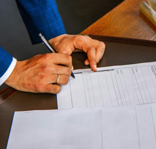 A person signing a contract. Hands zoomed in on an empty page. The person is holding a pen, about to sign.