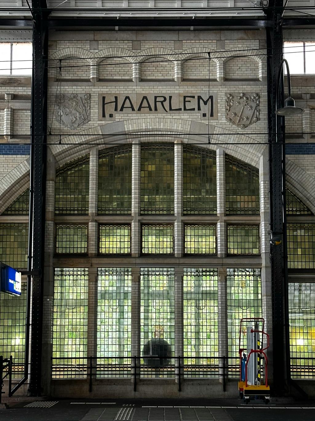 Haarlem Station – een grijs bakstenen gebouw met 'Haarlem' in reliëf, geflankeerd door twee wapens. 